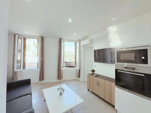 un salon avec une grande télévision et une table dans l'établissement Appartement 2 pieces rénové avec clim, Wi-Fi et tout équipé - Proche de rue d'Antibes et Palais des Festivals, à Cannes