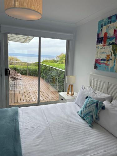 a bedroom with a bed and a view of a deck at Sandbar Beach House in Coles Bay