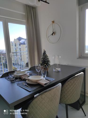 Una mesa de comedor con un árbol de Navidad y un reloj. en Lullaby apartment, moderan stan sa dvije spavaće sobe i besplatnim parkingom, en Bijeljina