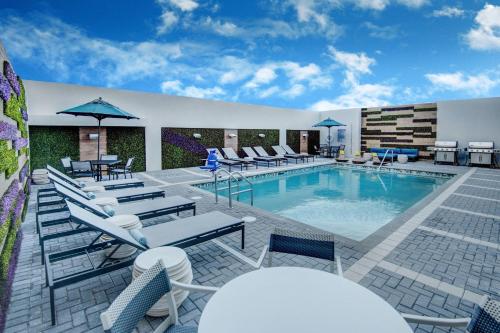 a swimming pool with lounge chairs and tables at TownePlace Suites by Marriott Miami Airport in Miami