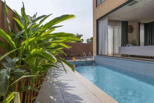 a swimming pool with plants next to a building at Vilasa 5 BHK by tisyastays in Vagator