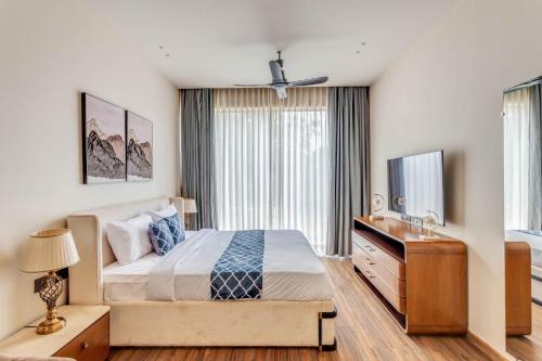 a bedroom with a bed and a dresser and a television at Vilasa 5 BHK by tisyastays in Vagator