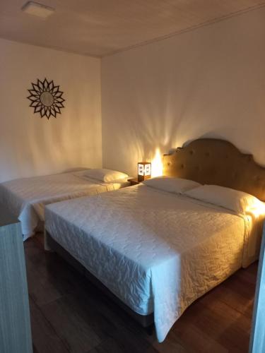 a bedroom with two beds and a light on the wall at Hospedaria Mitterer in Treze Tílias