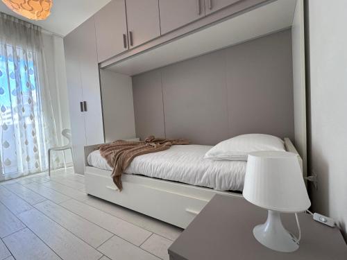 a white bedroom with a bed and a white lamp at Casa Helios by Ca-Sa Check in Chioggia