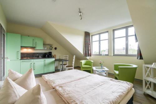 a room with a bed and a kitchen with green cabinets at An der Metow-Ferienpark Hotel in Plau am See
