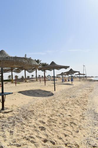 a beach with umbrellas and people on the sand at Golden Beach 2 Ras Sedr شالية على البحر قرية جولدن بيتش 2 راس سدر in Ras Sedr