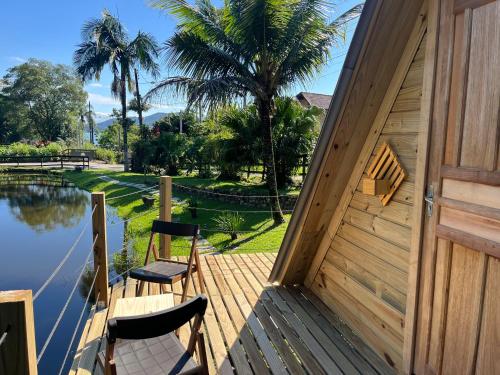 a wooden deck with two chairs and a door at Pousada Nosso Bosque in Porto Belo