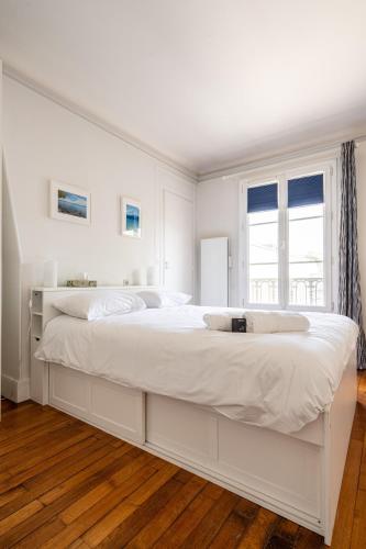 une chambre blanche avec un grand lit avec une fenêtre dans l'établissement Appartement Lumineux avec balcon proche paris - II, à Boulogne-Billancourt