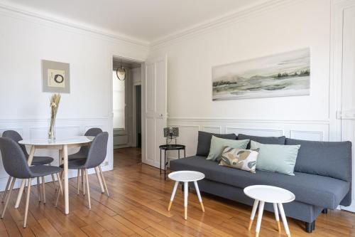 un salon avec un canapé bleu et une table dans l'établissement Appartement Lumineux avec balcon proche paris - II, à Boulogne-Billancourt