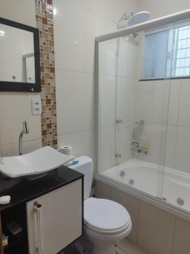 a bathroom with a toilet and a sink and a tub at Casa Central Super Conforto 78 in Ponta Grossa