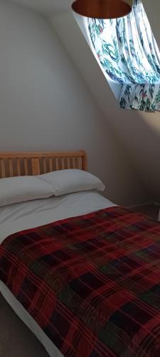 a bedroom with a bed with a comforter and a window at Harnham Flat in Salisbury
