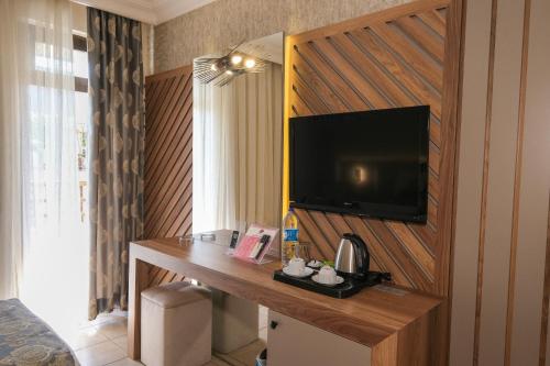 a room with a desk with a television on a wall at Kandelor Hotel in Alanya