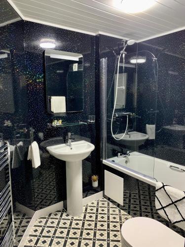 a black and white bathroom with a sink and a tub at Sarum Apart-Hotel in Saint Helier Jersey