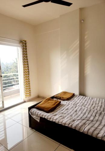 a bedroom with a bed and a large window at Whispering Wind Homestay in Kolhapur