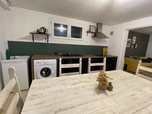 une cuisine avec une table et une machine à laver dans l'établissement Cosy appartement jardin centre ville, à Muzillac