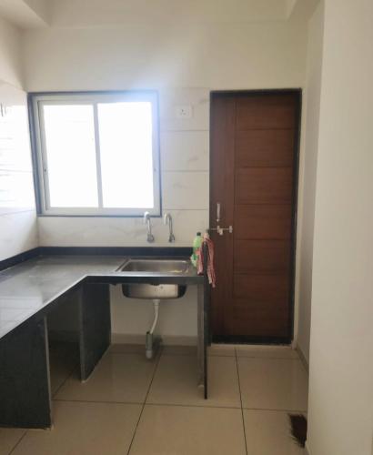 a kitchen with a sink and a window and a door at Whispering Wind Homestay in Kolhapur