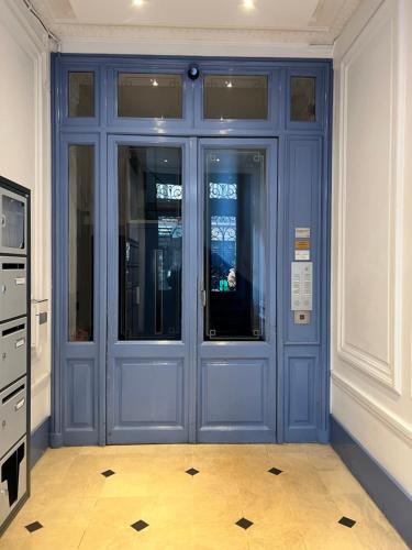 - une porte bleue dans un bâtiment doté de carrelage dans l'établissement APPARTEMENT AU CŒUR DE MARAIS DANS CENTRE de PARIS, à Paris