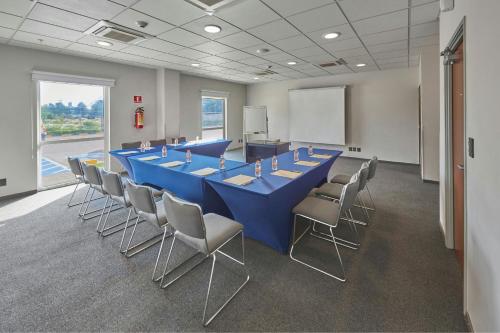 a conference room with a long blue table and chairs at City Express by Marriott Cananea in Cananea