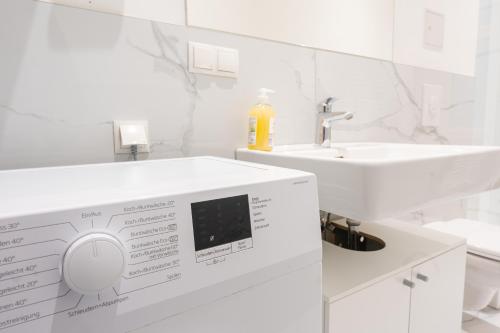 a white bathroom with a washing machine and a sink at Vienna City Apartments - Metro 1160 Vienna in Vienna