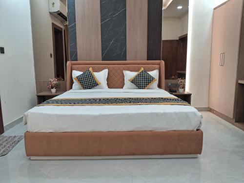 a bedroom with a large bed with a wooden headboard at Kaspar Suites in Greater Noida