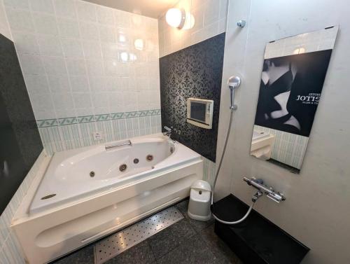 a bathroom with a tub and a toilet and a sink at HOTEL Pierrot 泉大津 in Izumiotsu