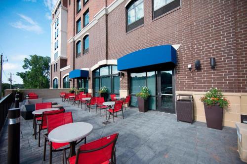 a patio with tables and red chairs in front of a building at Springhill Suites By Marriott Athens Downtown/University Area in Athens