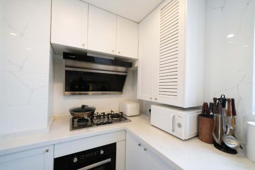 a kitchen with white cabinets and a stove top oven at Book and Bed-People's Square in Shanghai