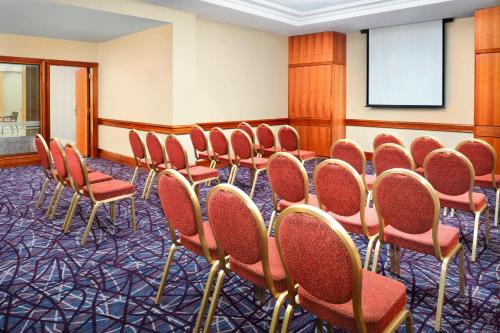 a conference room with red chairs and a whiteboard at Sheraton Skyline Hotel London Heathrow in Hillingdon