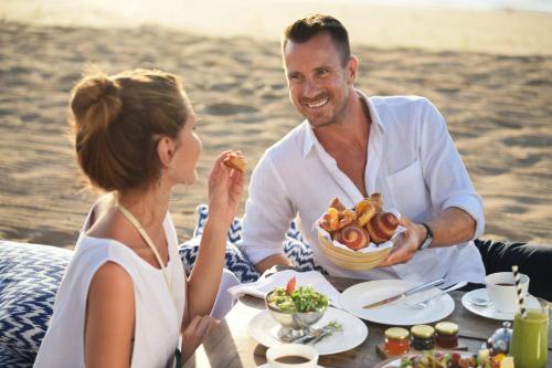 a man and a woman sitting at a table eating food at The St. Regis Bali Resort in Nusa Dua