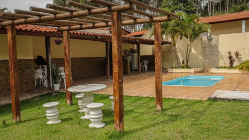 a pergola with a table and stool in a yard at Pousada Saint James in Águas de Lindóia