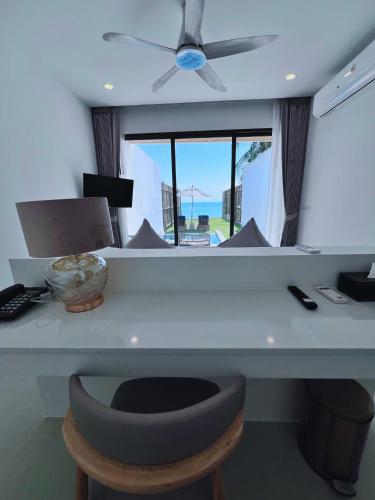 a room with a desk with a ceiling fan at Three Trees Samui Resort - Sarocha Villa in Lamai