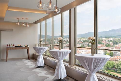 a room with two white tables and large windows at The Westin Zagreb in Zagreb