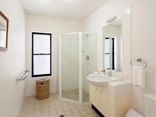 a white bathroom with a sink and a shower at The Point Coolum in Coolum Beach