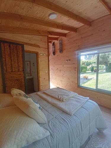 a bedroom with a bed in a log cabin at La Cabana de Cocholgüe 45 in Tomé
