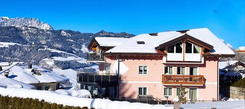 ein rosa Haus mit Schnee auf dem Dach mit Bergen in der Unterkunft Appartement Gern in Alpendorf
