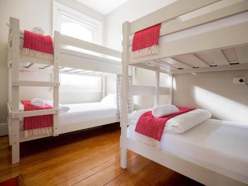 a bedroom with two bunk beds with red towels at Montacute Boutique Bunkhouse in Hobart