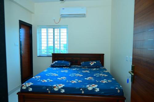 a bedroom with a blue bed with blue sheets and a window at Vaarahi Guest Inn in Nellore