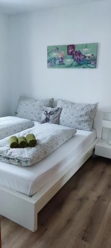 a white bed with two green pillows on it at Appartement Gern in Alpendorf