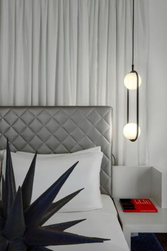 a bedroom with a bed with a plant and a lamp at W London in London