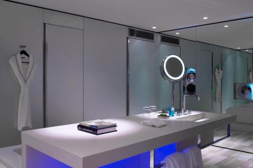 a white bathroom with a sink and a mirror at W London in London
