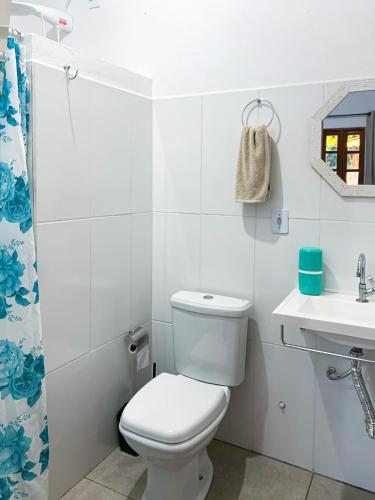 a white bathroom with a toilet and a sink at Chales Estiva Nova in Mucugê