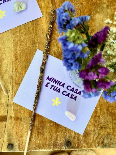 a table with flowers and a card and a vase of flowers at AumHome Guesthouse in Aljezur