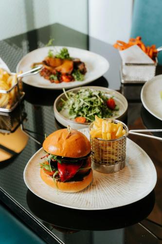 three plates of food on a table with a hamburger and fries at W London in London