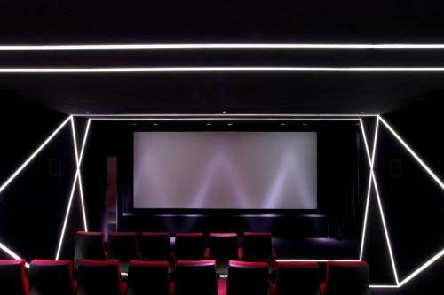 a theatre with red chairs in front of a screen at W London in London