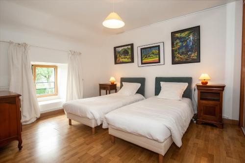deux lits dans une chambre avec des draps blancs dans l'établissement Maison de campagne en centre Finistère, à Lennon