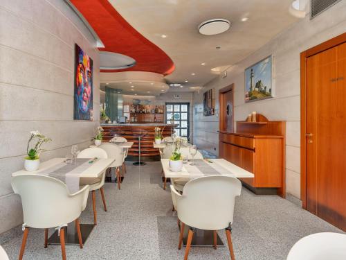 a restaurant with white tables and white chairs at B&B HOTELS Hotel Prestige Ornago in Ornago