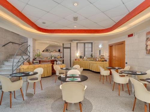 a restaurant with tables and chairs and a staircase at B&B HOTELS Hotel Prestige Ornago in Ornago