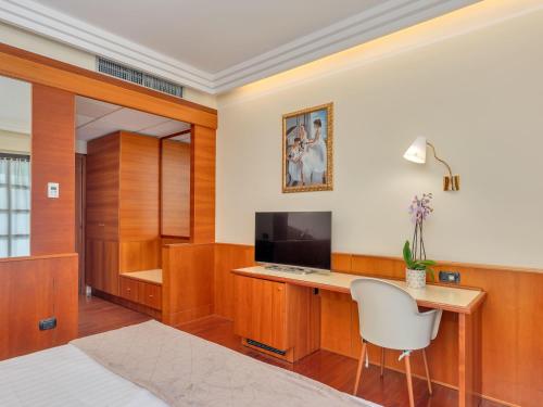 a bedroom with a desk with a television and a chair at B&B HOTELS Hotel Prestige Ornago in Ornago