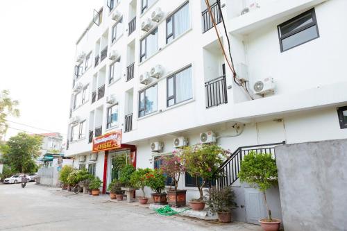 a white building with potted plants on a street at NOI BAI AIRPORT Hotel-内排华星酒店 in Hanoi