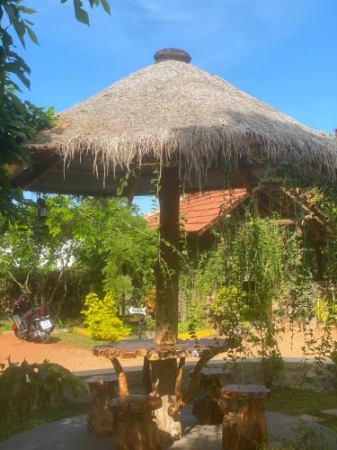 a large straw umbrella with a table and a motorcycle at Hotel Hanguk Villa in Dambulla